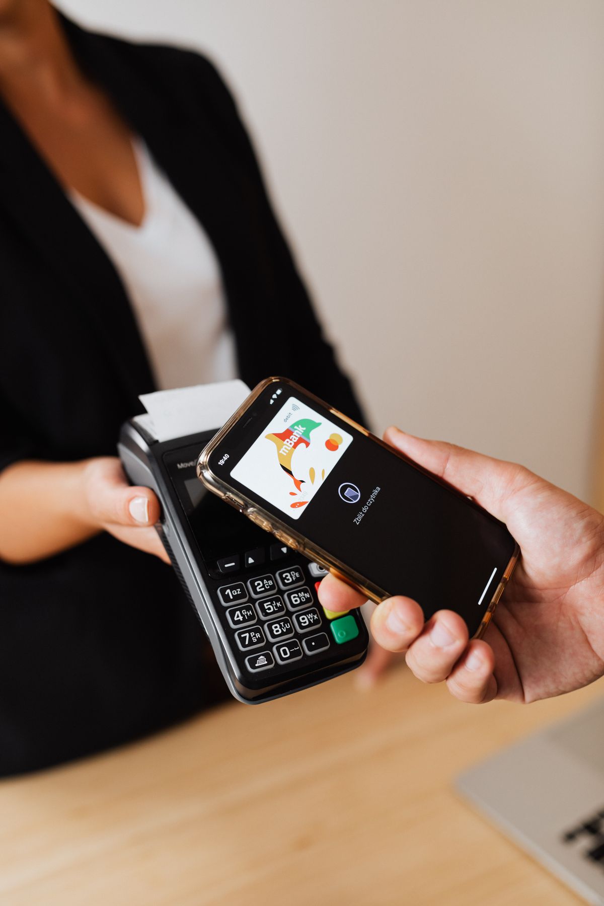 Tangan memegang HP yang menampilkan aplikasi m-banking saat membayar di mesin pembayaran, menggambarkan pembayaran pajak kendaraan yang kini bisa dilakukan lewat HP tanpa antre di loket