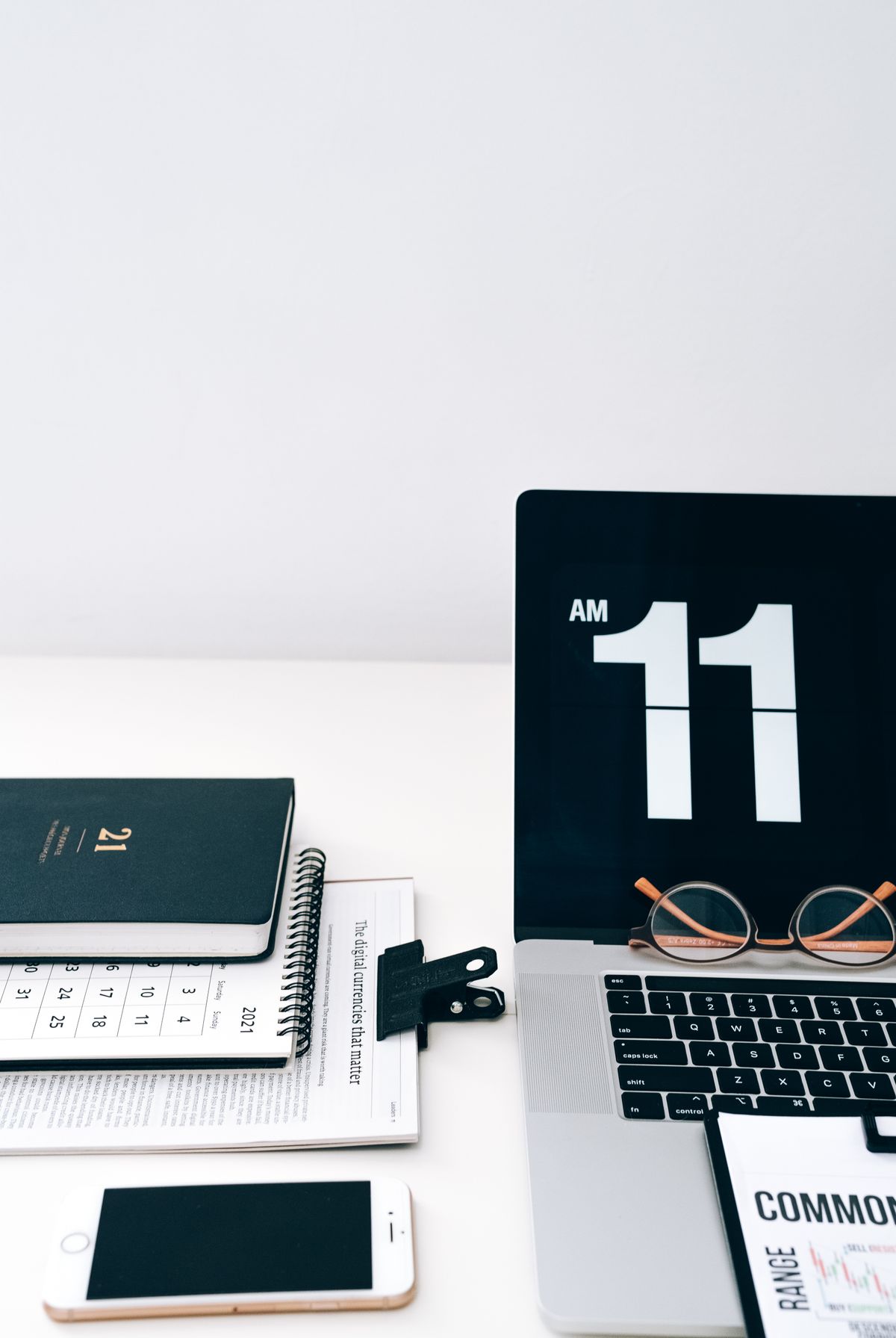 Meja kerja dengan laptop yang menampilkan jam digital, kalender, dan HP, menggambarkan pengaturan jadwal pengiriman pesan