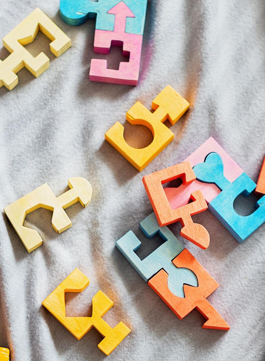 Potongan puzzle kayu warna-warni berbentuk balok dengan berbagai bentuk tersebar di atas kain, menggambarkan balok warna dalam game puzzle