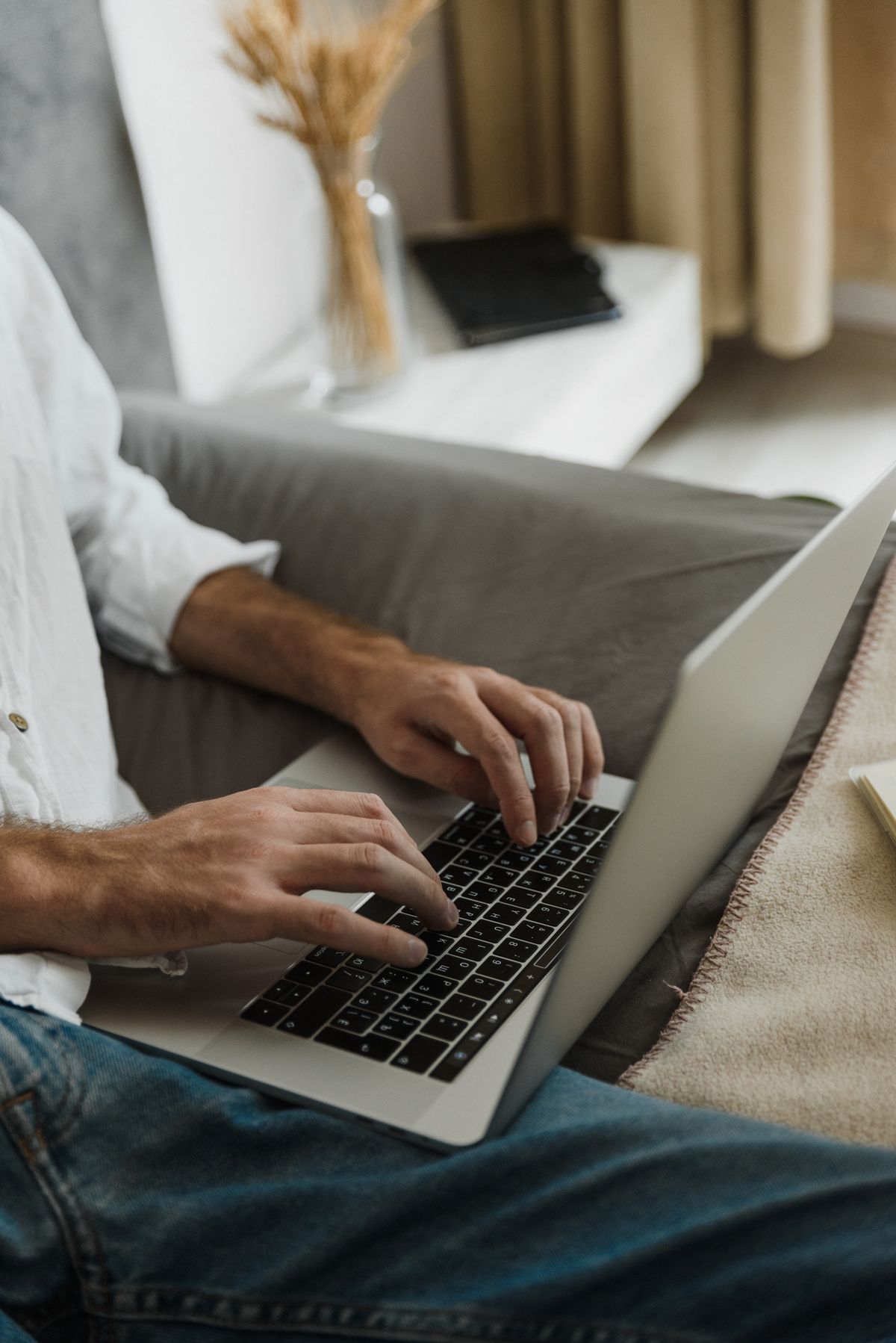 Seseorang mengetik di laptop sambil duduk santai di rumah, menggambarkan kamu bisa mengerjakan dokumen Word versi web gratis dari mana saja tanpa memasang aplikasi