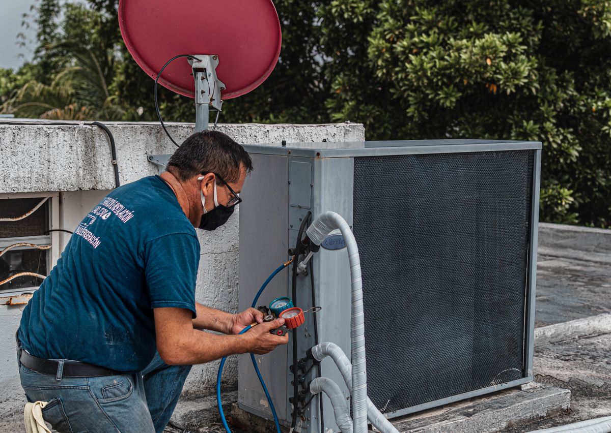 Teknisi sedang memeriksa unit AC di luar rumah, salah satu alat elektronik yang paling banyak menyedot daya listrik rumah
