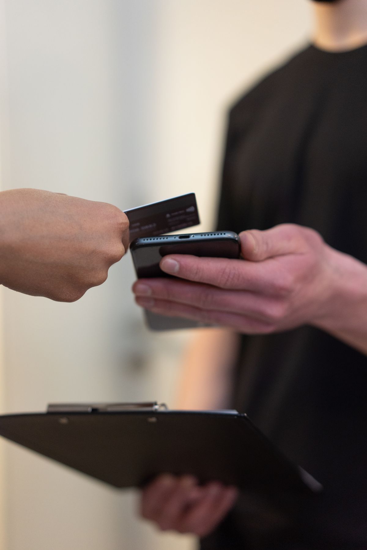 Seseorang melakukan pembayaran nontunai dengan menempelkan kartu ke HP, menggambarkan pembayaran digital lintas negara