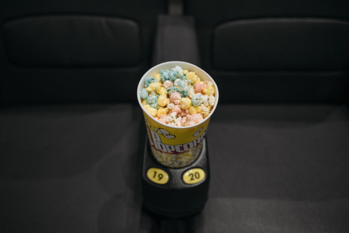 Ember popcorn warna-warni di sandaran kursi bioskop